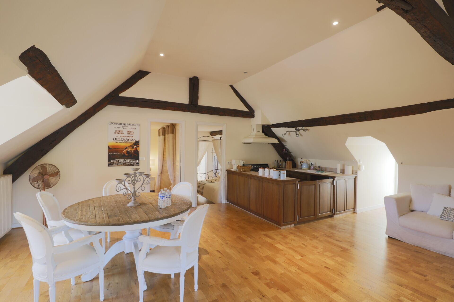 A spacious loft with a wooden dining table, white chairs, a kitchen area, and a cozy seating area.