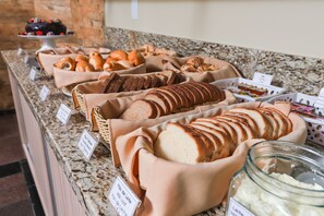 A bakery display with various breads and pastries, including a loaf of bread and croissants, on a granite countertop. - Hotel Express Terminal Tur - Rodoviária Porto Alegre (Porto Alegre)