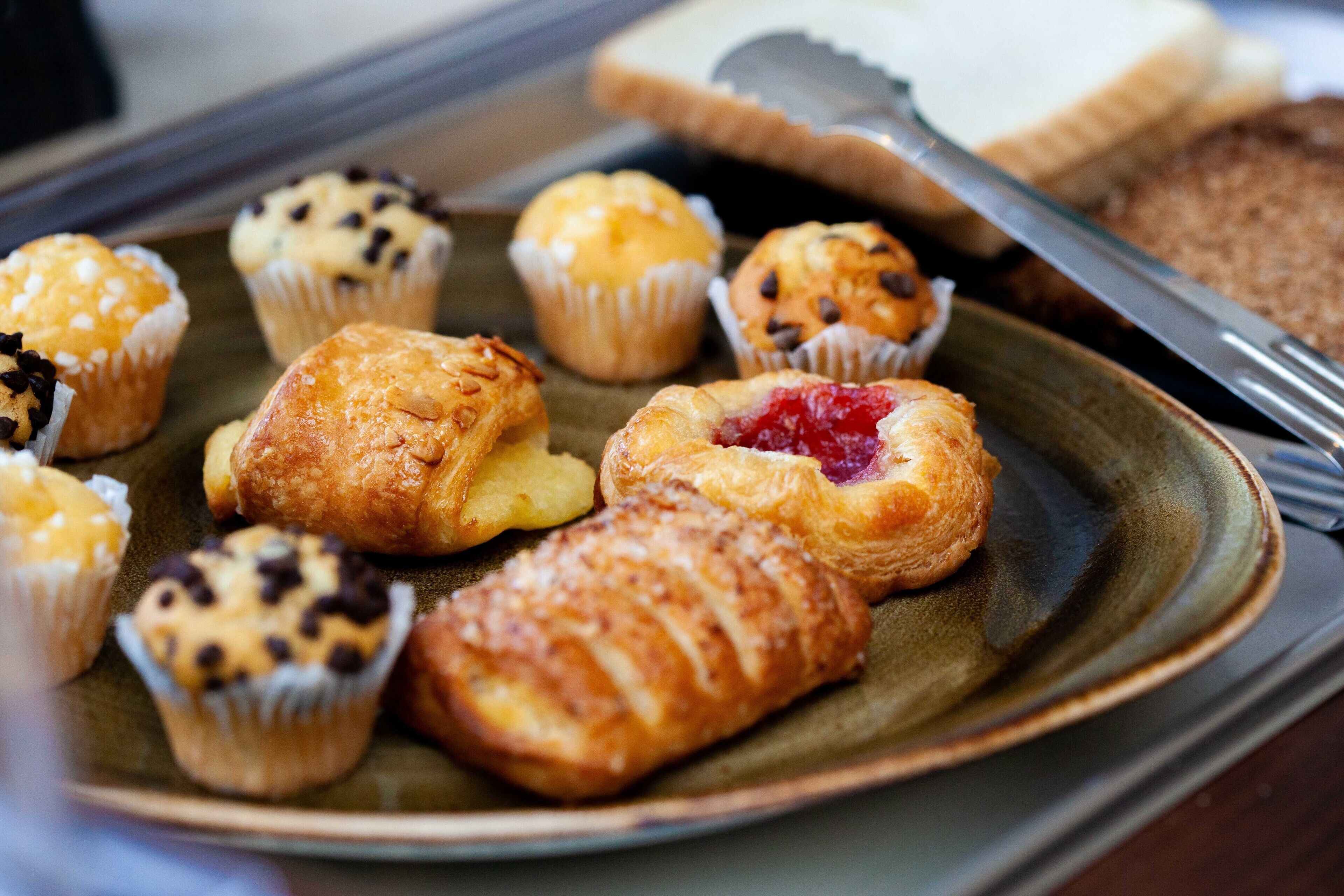 Une variété de viennoiseries présentées sur une assiette, notamment des muffins et des croissants.