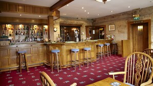 A bar area with wooden stools, a bar counter, and a red carpeted floor. - Woodsome Hall Golf Club Cottage on the Course (Huddersfield)