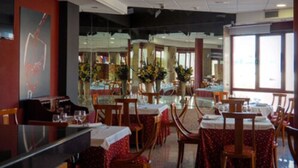 A restaurant with tables and chairs, a counter, and large windows.