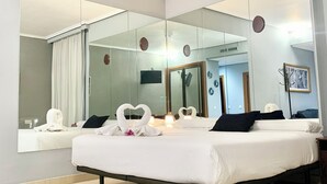 A modern hotel room with a large bed, a large mirror, and a view of the hallway.