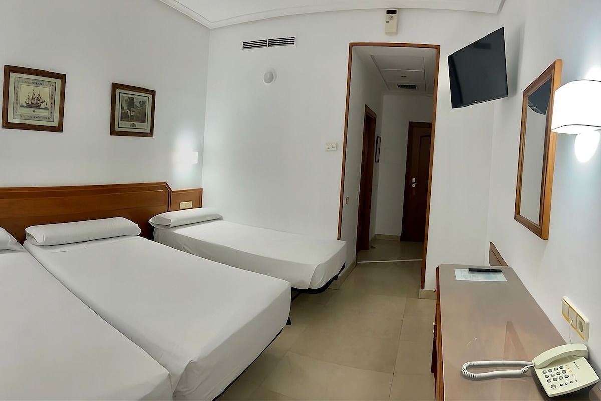 Ein Hotelzimmer mit zwei Einzelbetten, einem Schreibtisch mit Telefon und einem Spiegel.