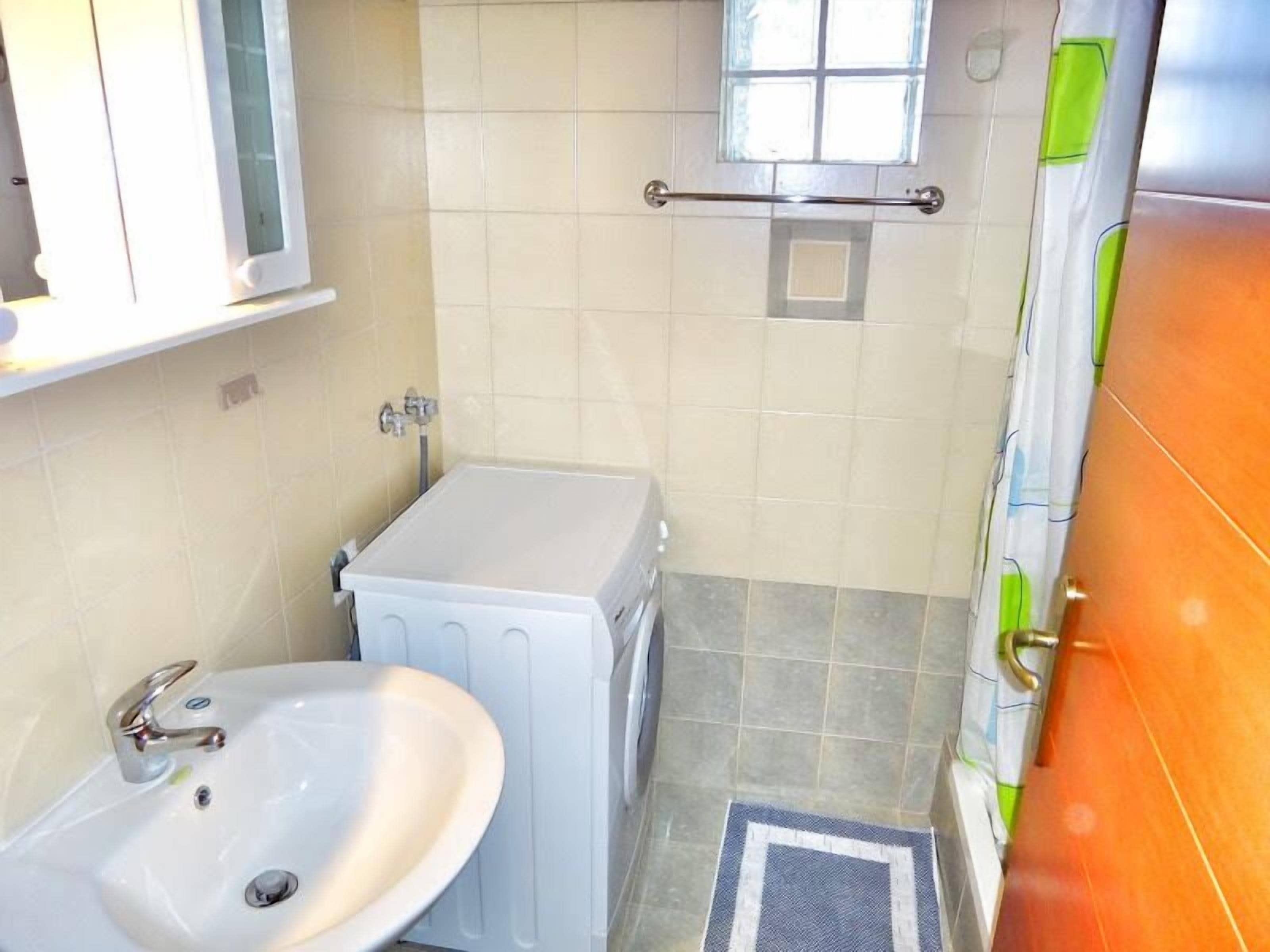 A small bathroom with a sink, toilet, and window.