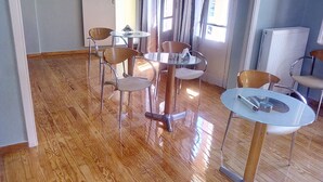 Una habitación con suelo de madera, una mesa redonda de cristal y cuatro sillas.