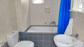 Une salle de bain comprenant des toilettes, un bidet, une baignoire et un lavabo.