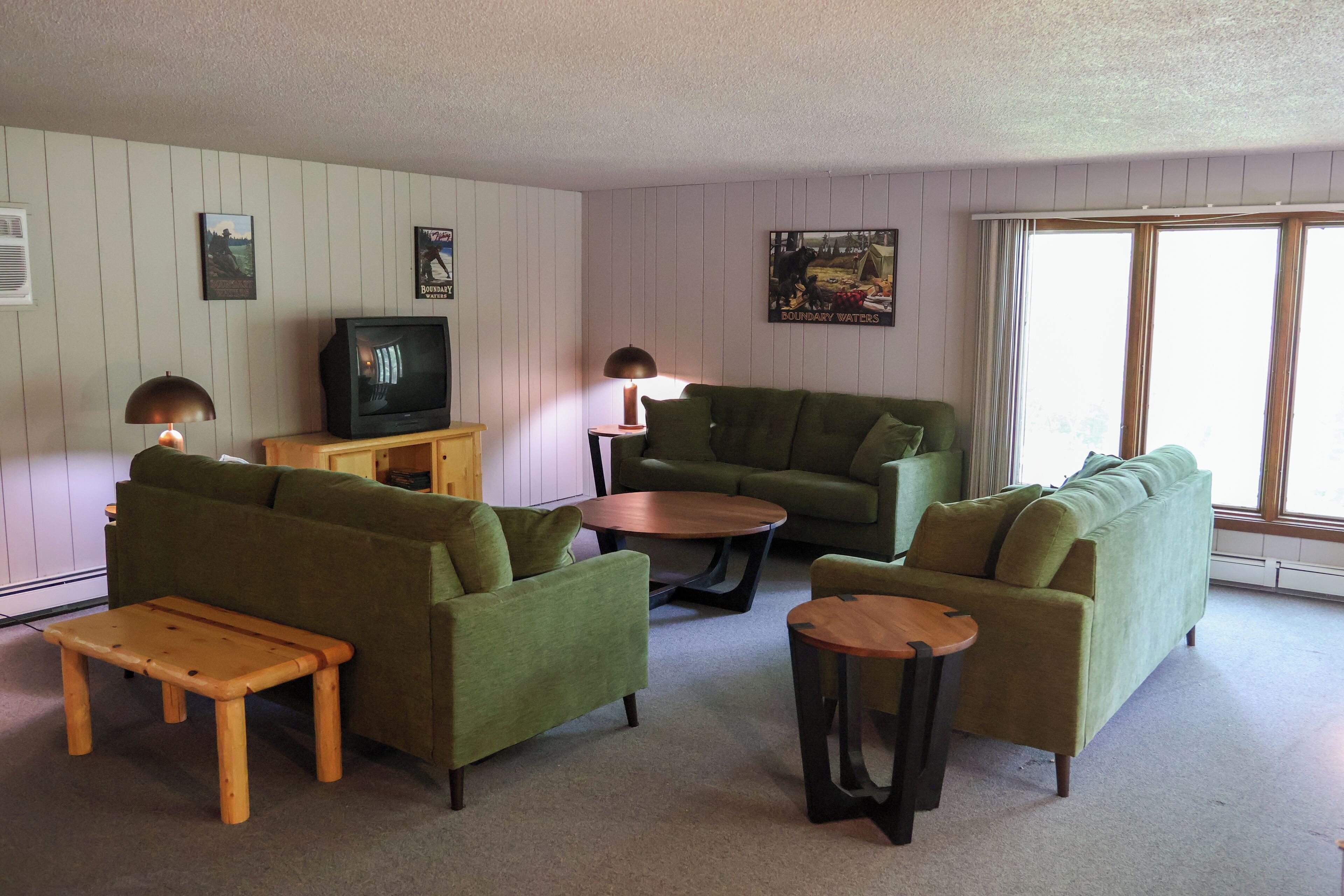 A living room with green sofas, a wooden coffee table, and a television.