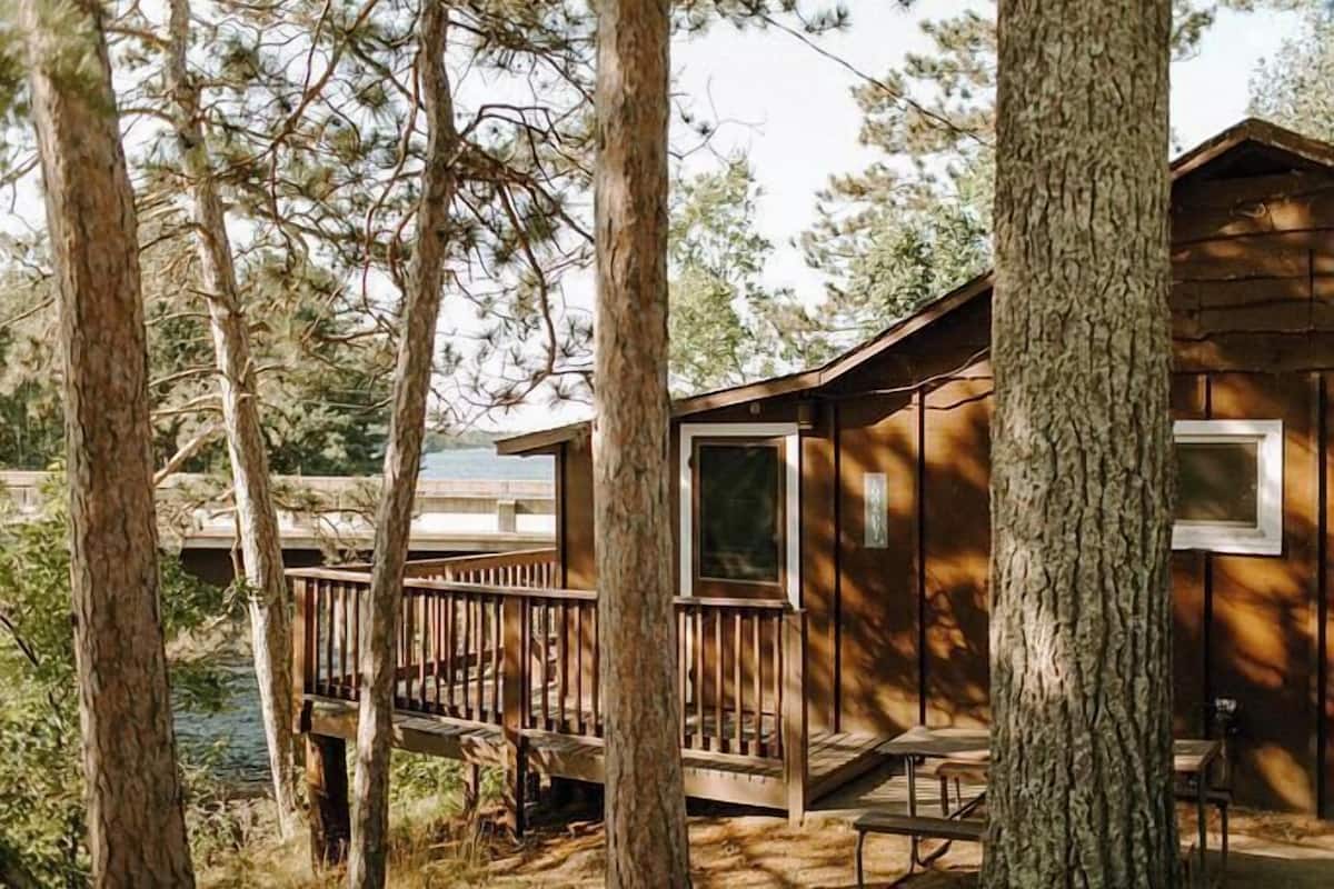 Una cabaña con terraza, rodeada de árboles.