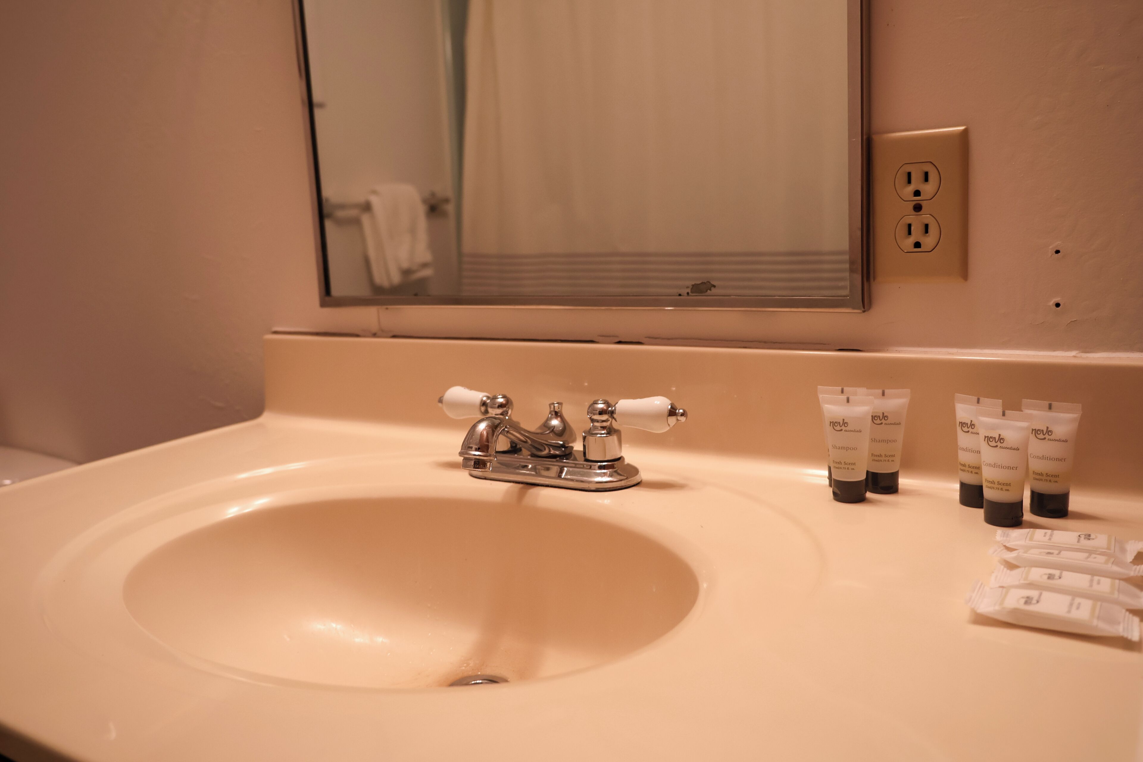 Un lavabo con uno specchio sopra, un portasciugamani e articoli da toilette sul ripiano.
