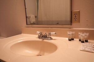 Un lavabo con uno specchio sopra, un portasciugamani e articoli da toilette sul ripiano.