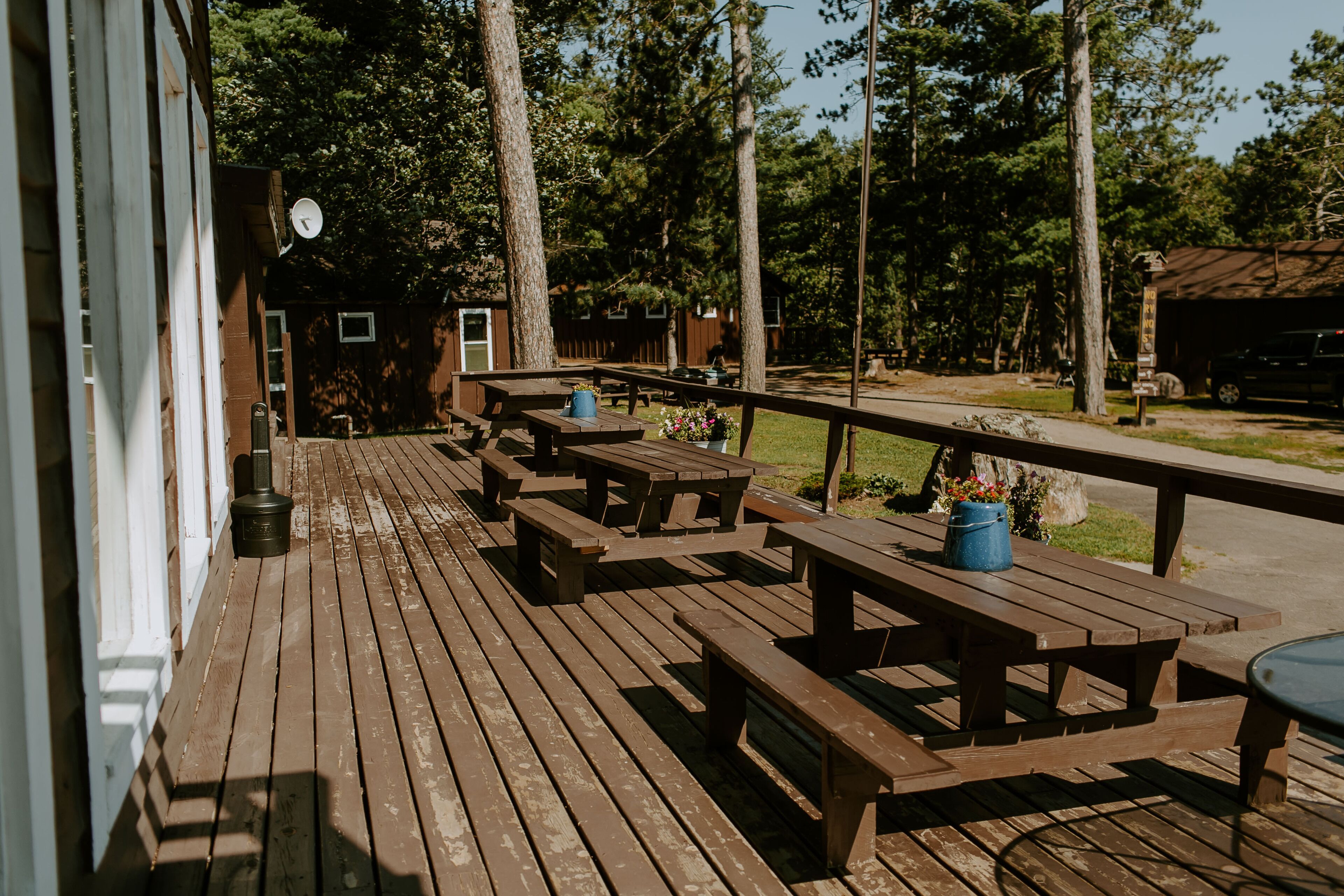 A wooden deck with picnic tables and a metal railing.