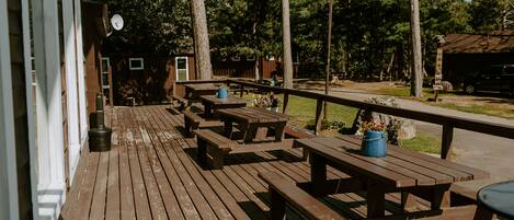 A wooden deck with picnic tables and a metal railing.