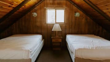 A room with two single beds, a window, and a lamp.