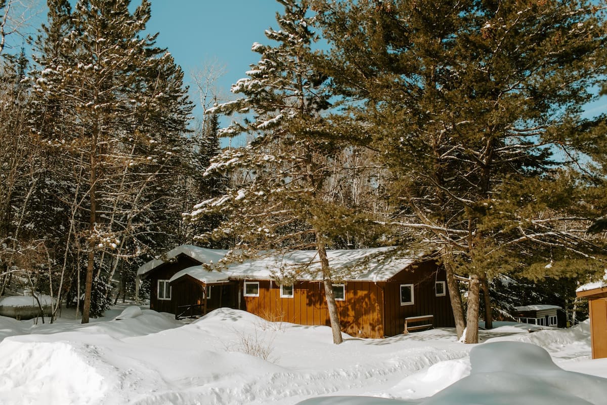 Una cabaña de madera rodeada de árboles cubiertos de nieve.