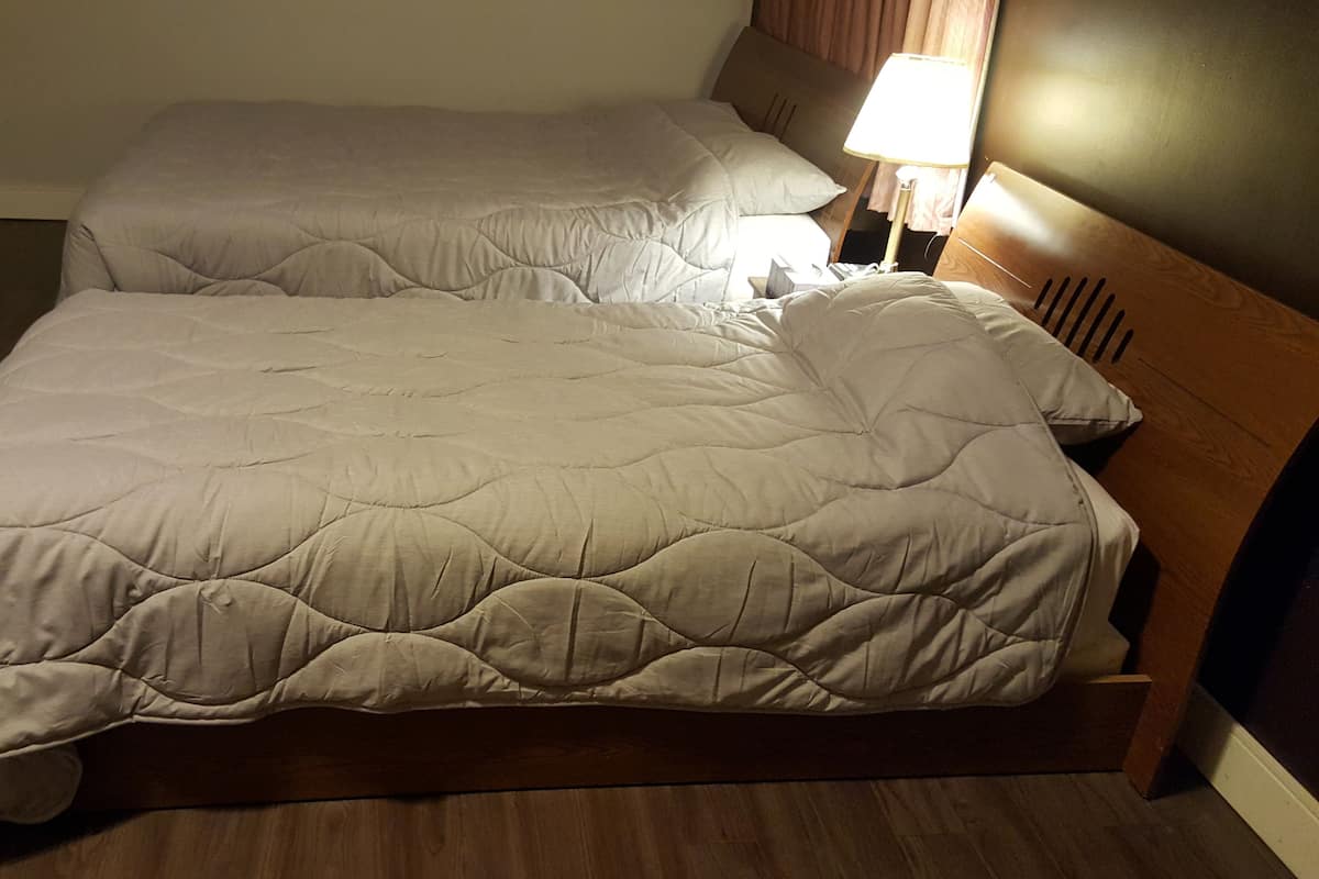 A double bed with a wooden frame and a quilted bedspread.