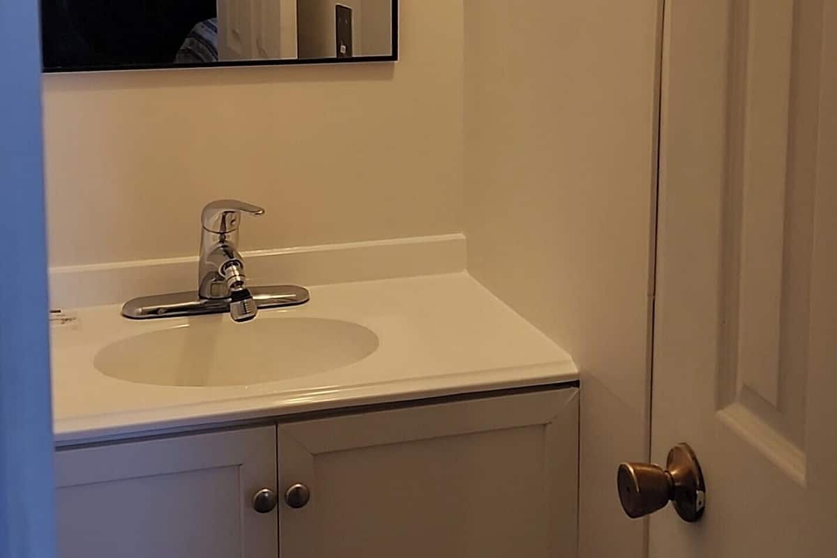 A bathroom with a white sink, a mirror, and a door.