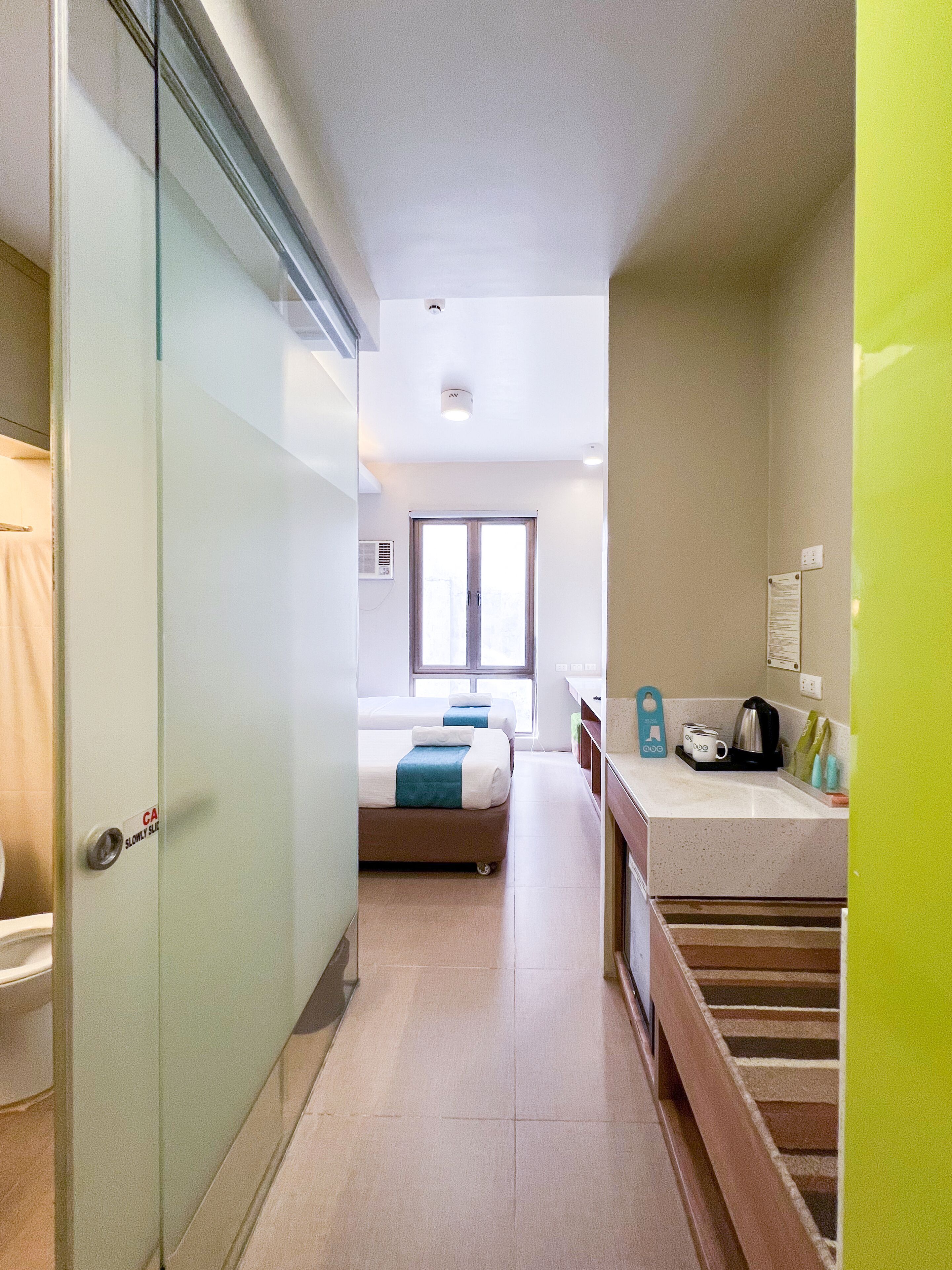 A hotel room with a bed, a bathroom, and a kitchenette.
