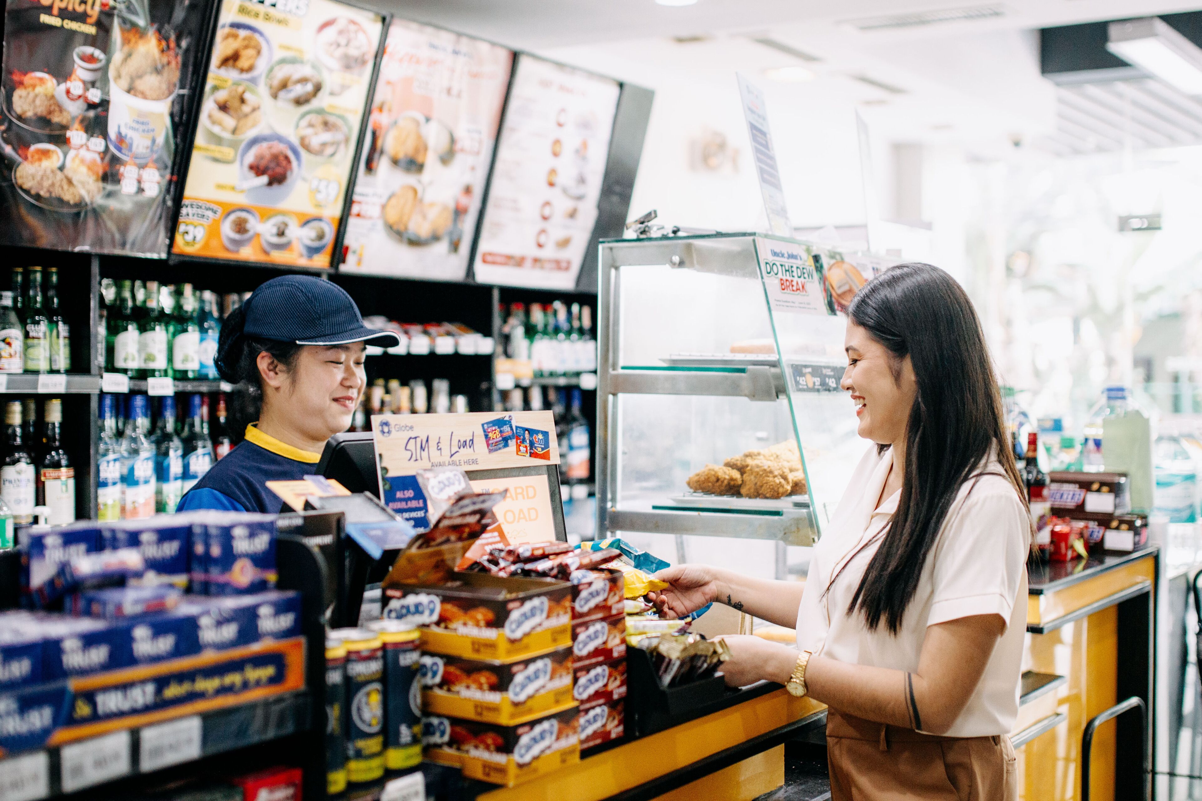Una persona frente a un mostrador en una tienda, posiblemente una panadería o charcutería, con diversos alimentos y condimentos a la vista.