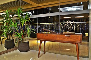 Un intérieur moderne agrémenté d’un meuble en bois, de plantes en pot et d’une sculpture d’arbre décorative.