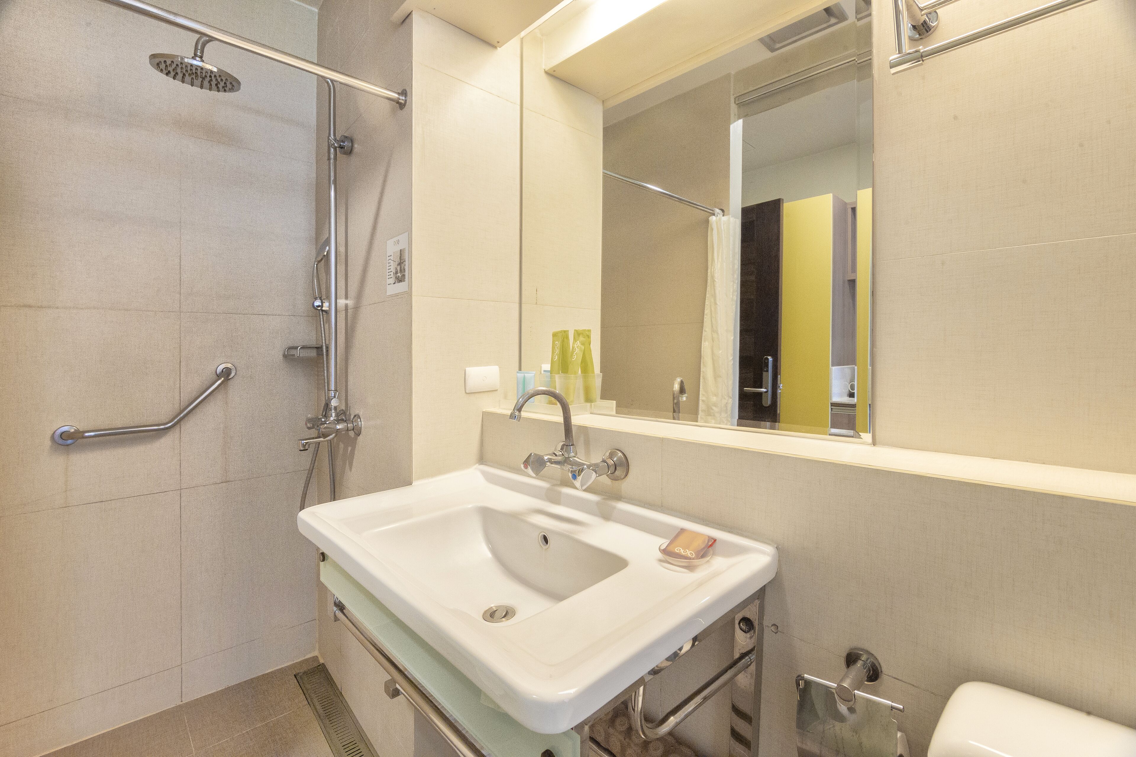 Un baño moderno con ducha, barra de apoyo, lavamanos e inodoro.