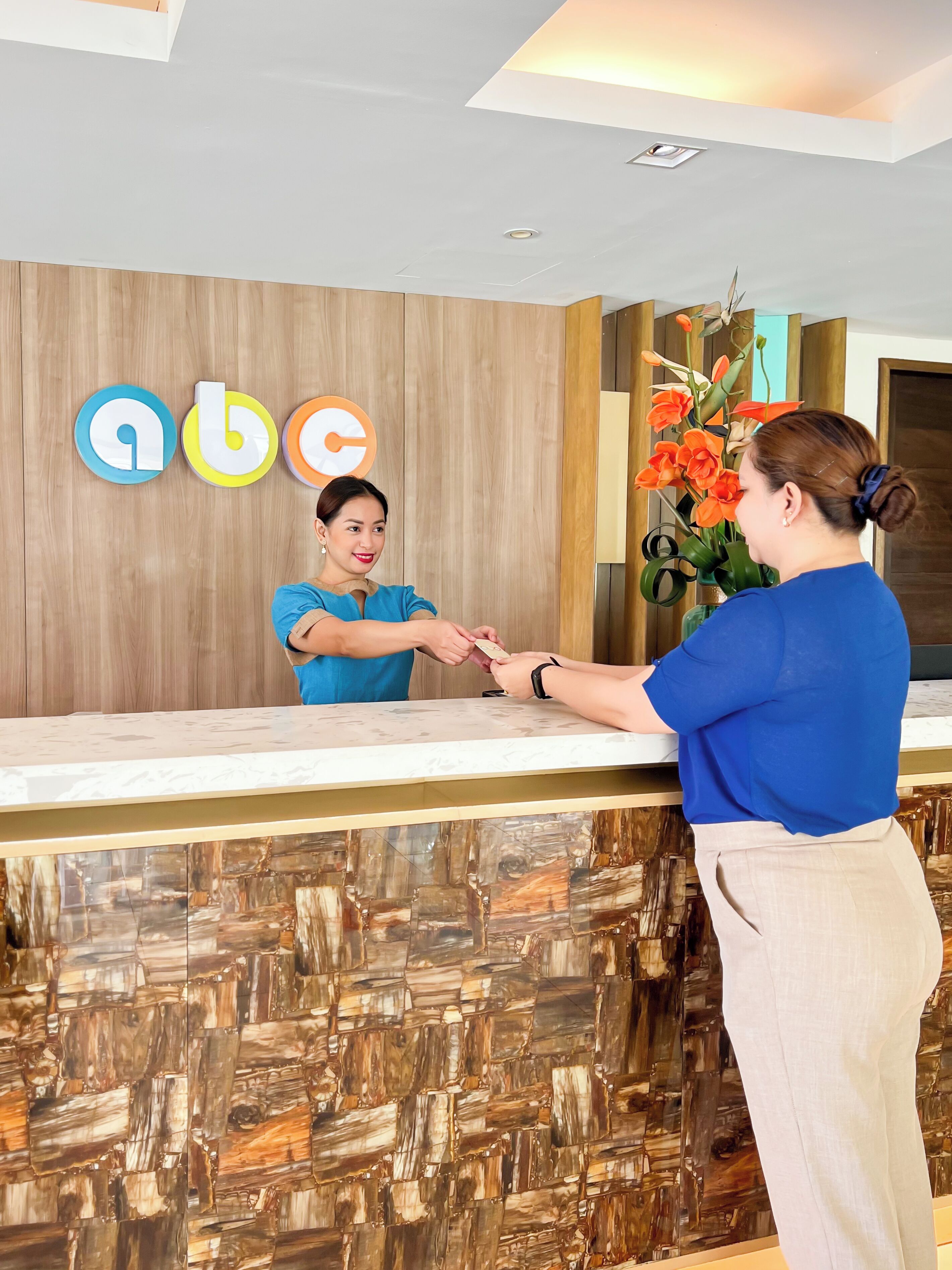 A reception desk with a wooden panel wall and a marble counter.