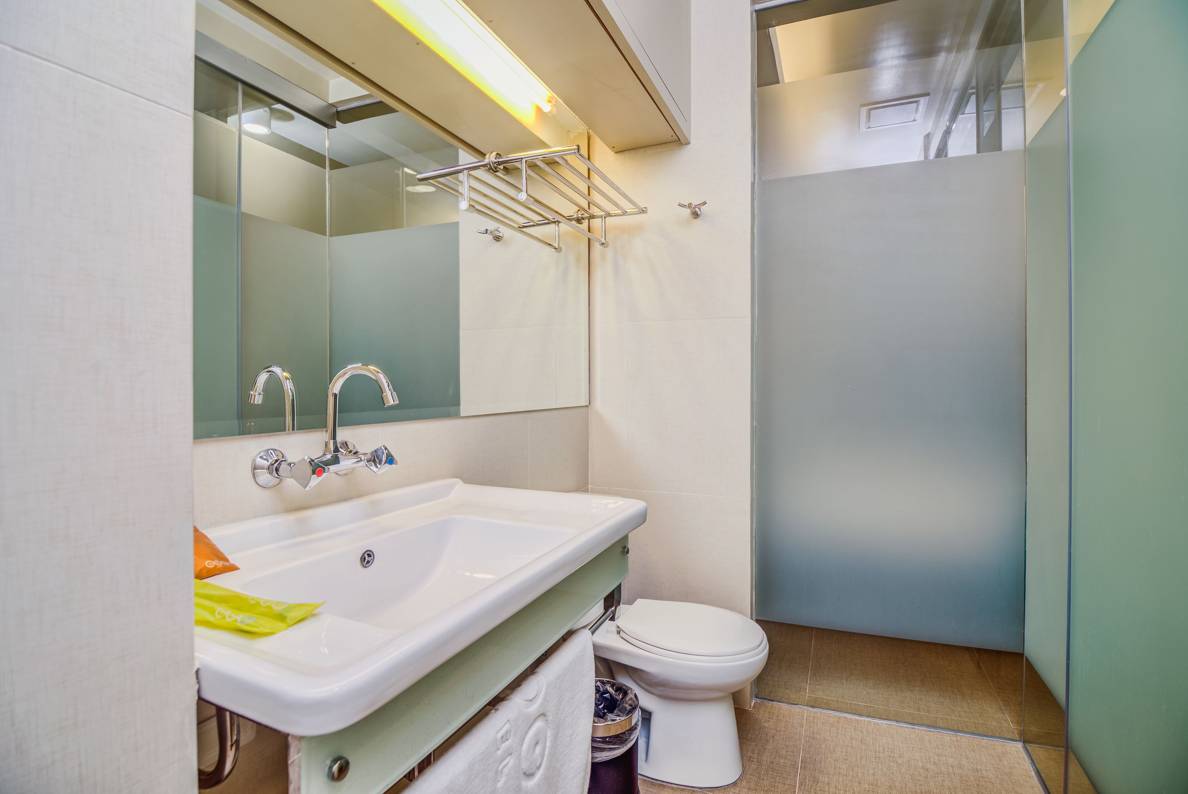 A bathroom with a sink, mirror, towel rack, toilet, and shower area.