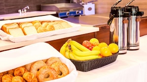 Un buffet de petit-déjeuner comprenant du pain, des viennoiseries, des bananes et des citrons.