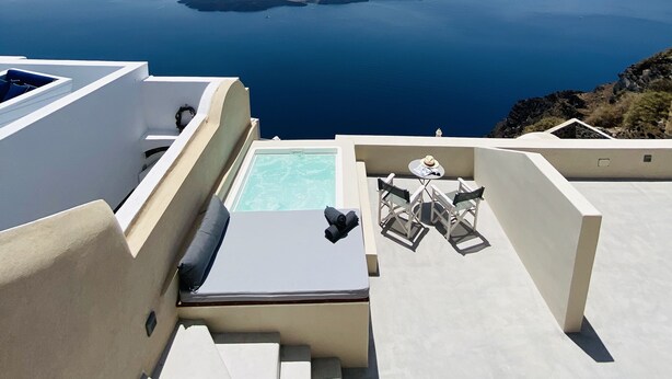 A rooftop terrace with a pool, seating area, and a view of the sea and islands. - Ikia Kriton (Santorini)
