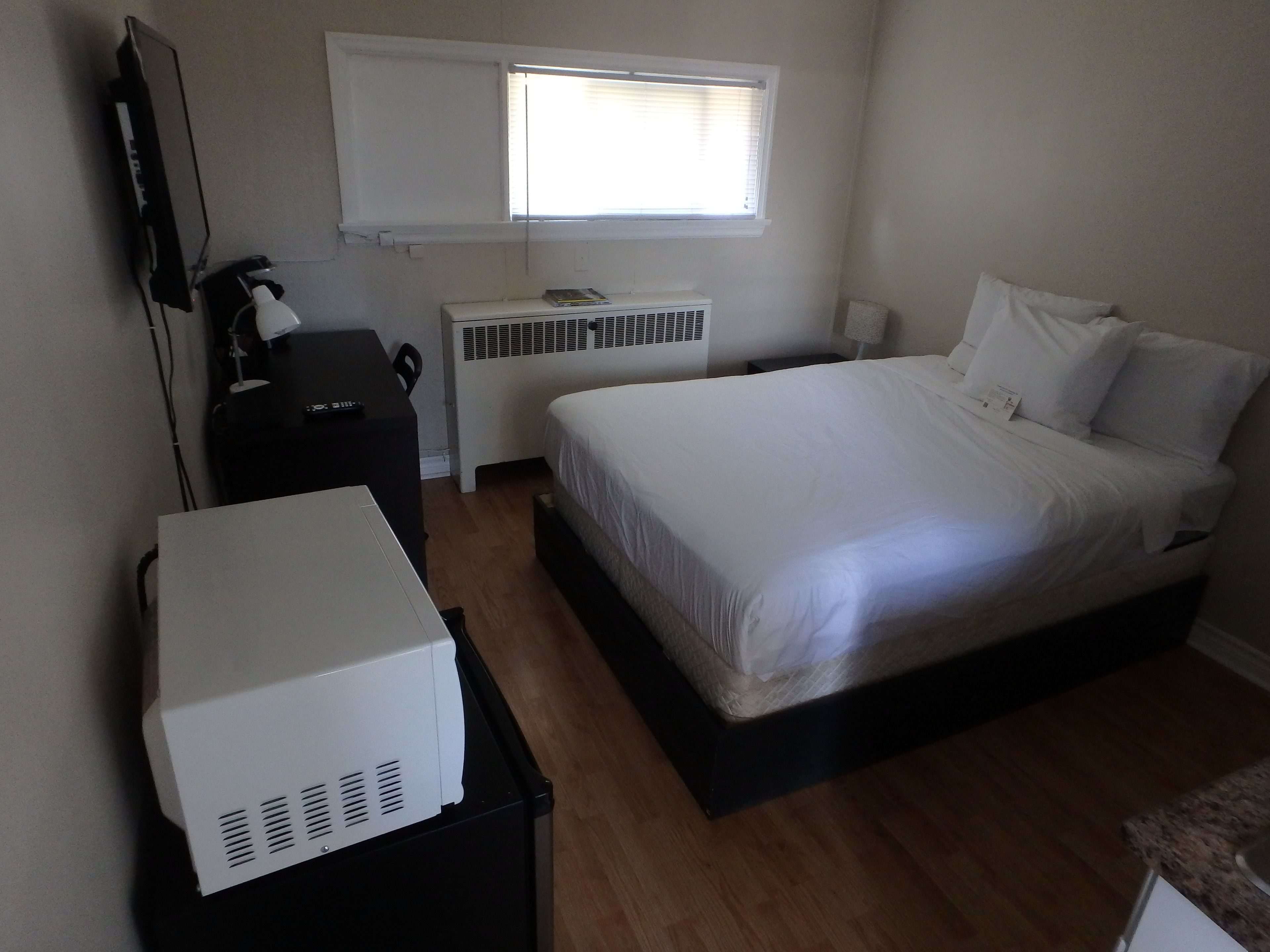 Un dormitorio con cama, escritorio, calefactor y ventana.