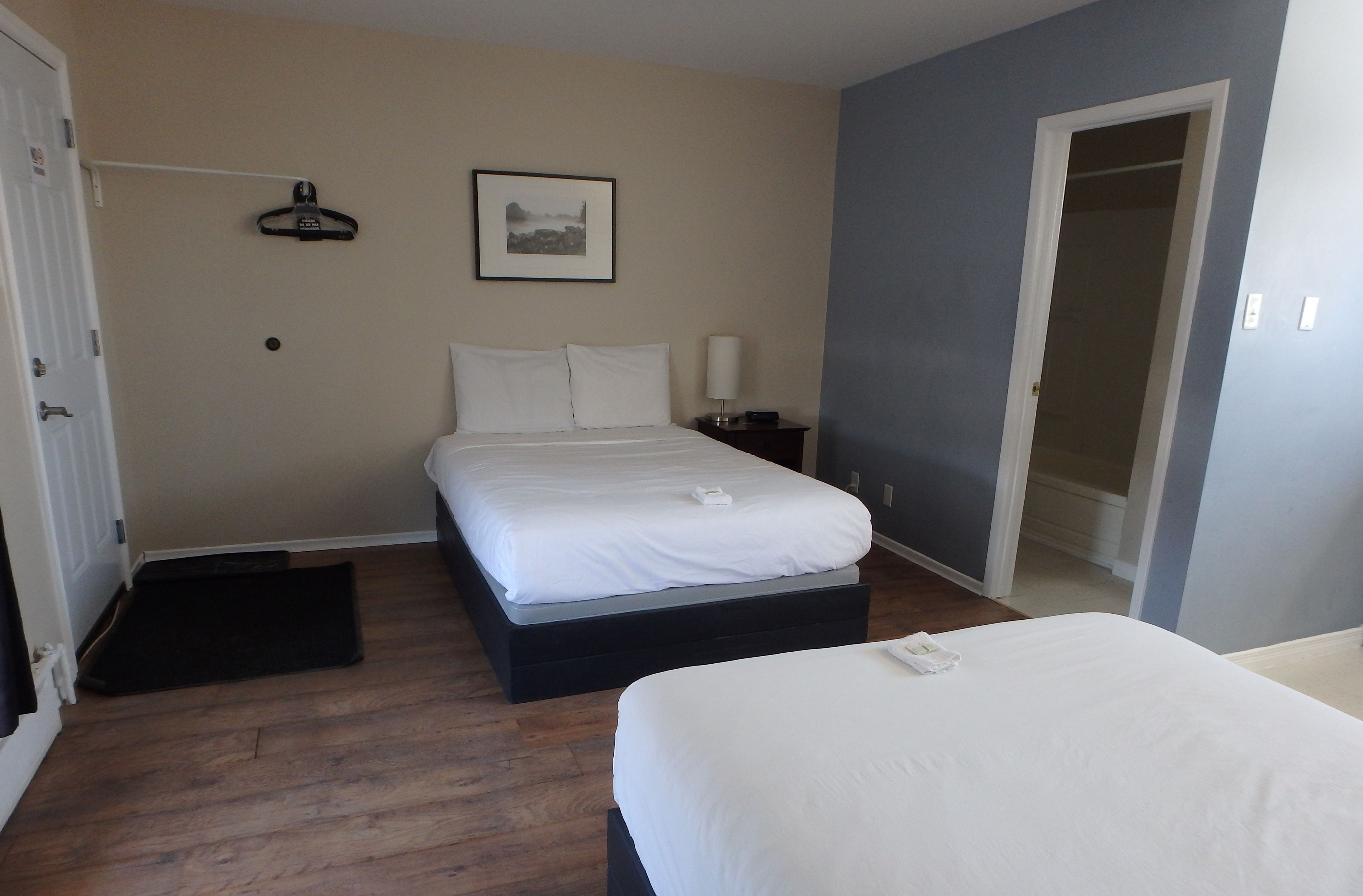 Una habitación de hotel con una cama, mesita de noche y una puerta.