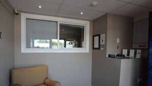 A room with a window, a chair, a reception desk, and a door. - Wheel Inn Motel (Temiskaming Shores)