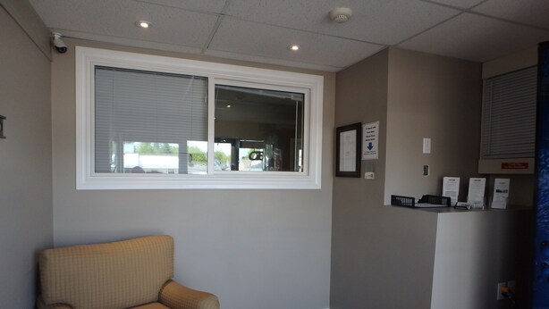 A room with a window, a chair, a reception desk, and a door. - Wheel Inn Motel (Temiskaming Shores)