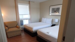 A hotel room with two beds, a chair, a window with blinds, and a framed picture on the wall. - Wheel Inn Motel (Temiskaming Shores)