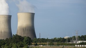 Two large cooling towers at a power plant with smoke rising from them. - Econo Lodge Athens I-75 (Athens)