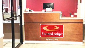 A reception desk with a red wall and a Dell computer monitor. The logo 'EconoLodge' and location 'Athens, TN' are visible. - Econo Lodge Athens I-75 (Athens)