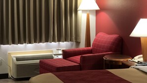A hotel room with a bed, a desk, a chair, a lamp, an air conditioner, and a window with curtains. - Econo Lodge Athens I-75 (Athens)