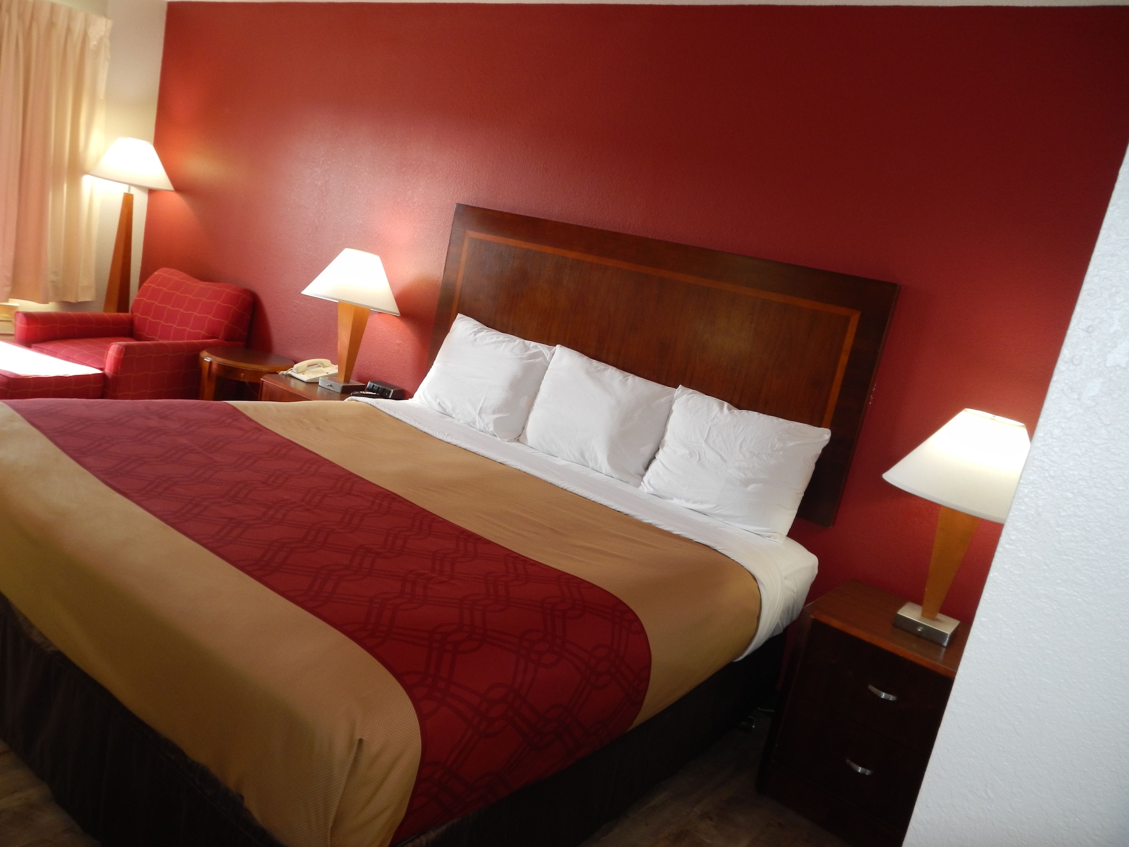 A hotel room with a large bed, red walls, and two bedside lamps.