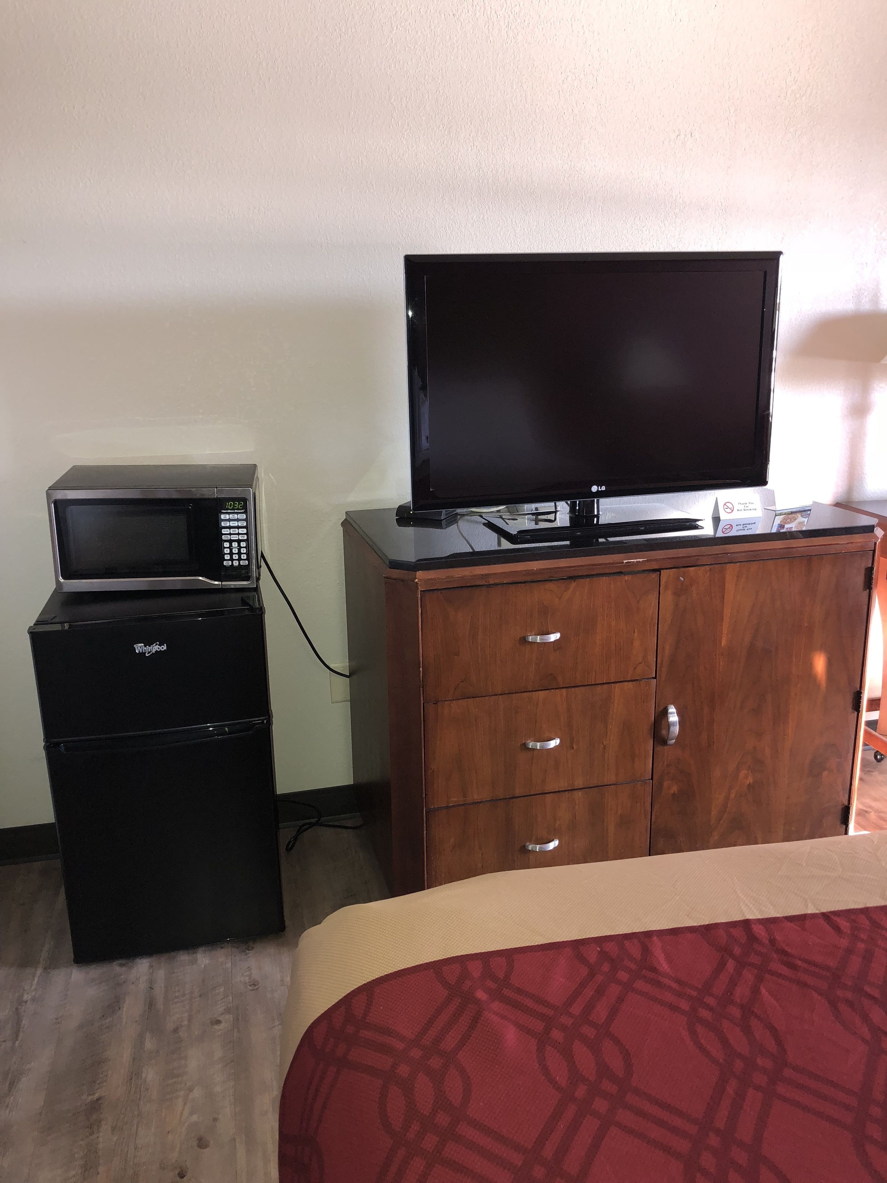 Una habitación de hotel con una cama, un aparador de madera, un microondas y un televisor.
