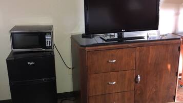 Una habitación de hotel con una cama, un aparador de madera, un microondas y un televisor.