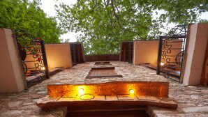 An outdoor seating area with stone flooring and metal railings, surrounded by trees. - Palios Stathmos (South Pelion)