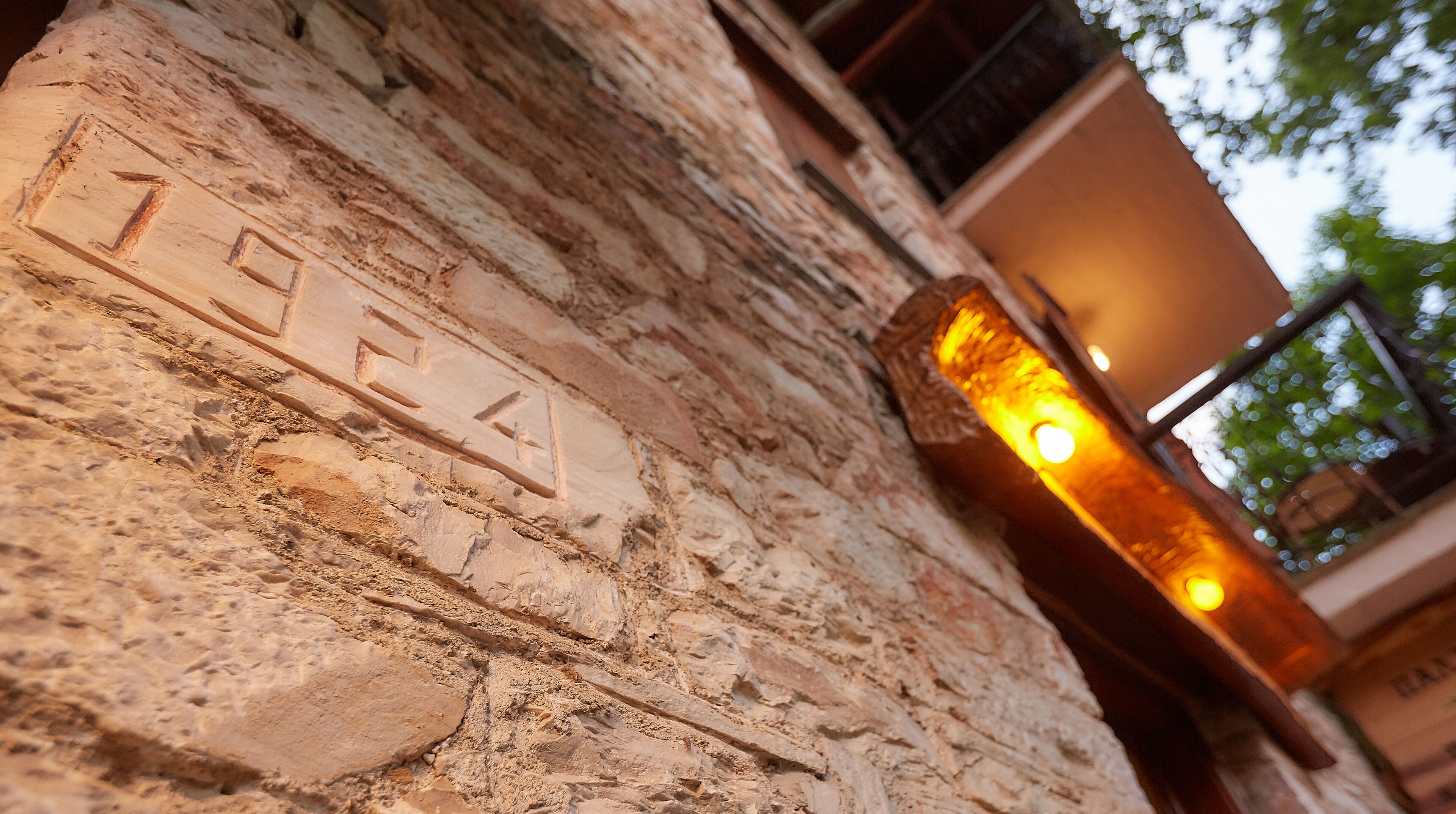 A stone wall with carved letters and a modern light fixture.