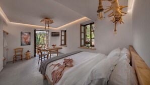 A modern bedroom with a large bed, a dining area, and a view of the outdoors. - Palios Stathmos (South Pelion)