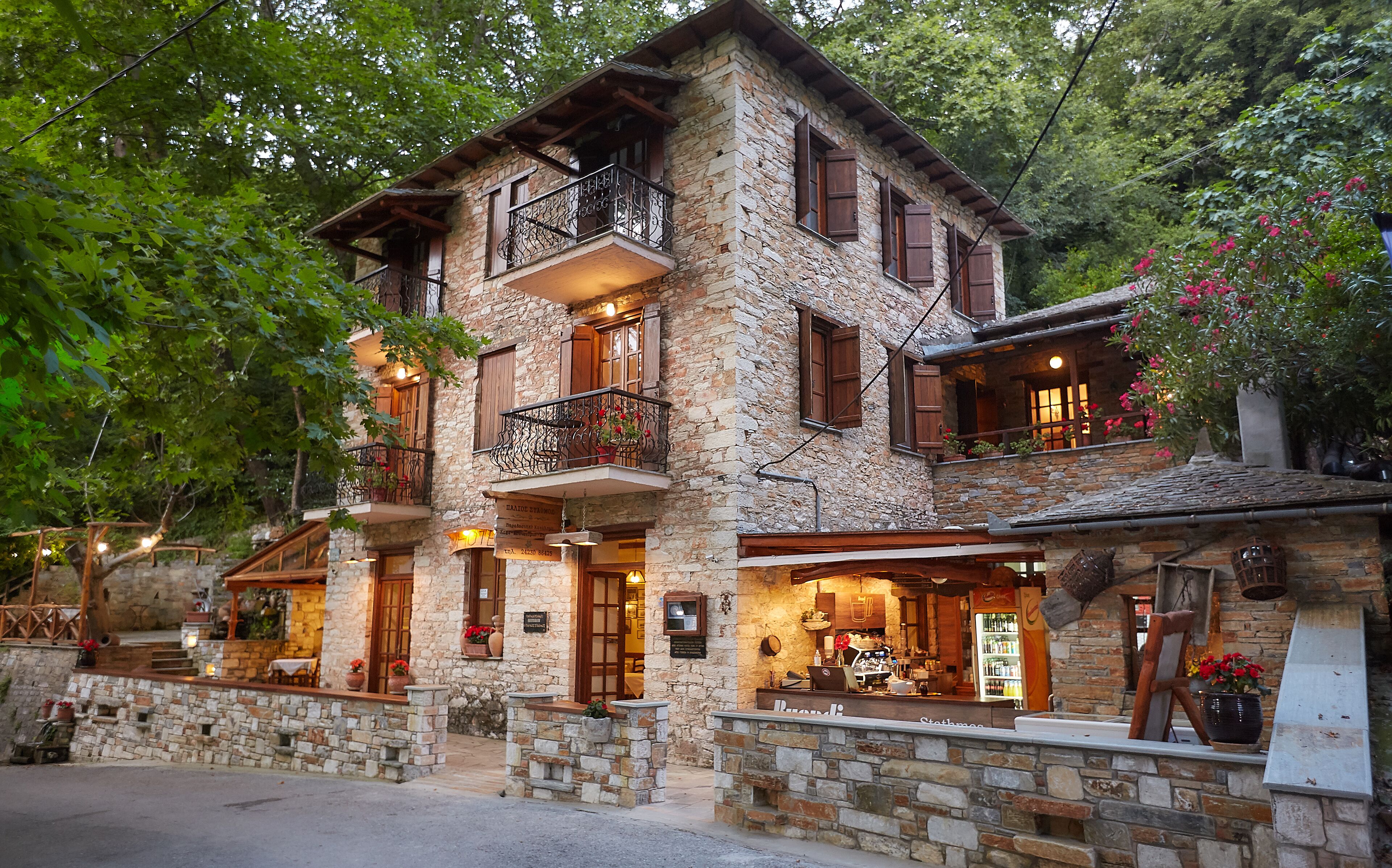 Un edificio de piedra con balcón, zona de bar y restaurante.
