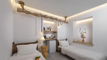 Quarto de hotel com duas camas, uma kitchenette pequena, uma estante de madeira com flores e um design rústico no teto.
