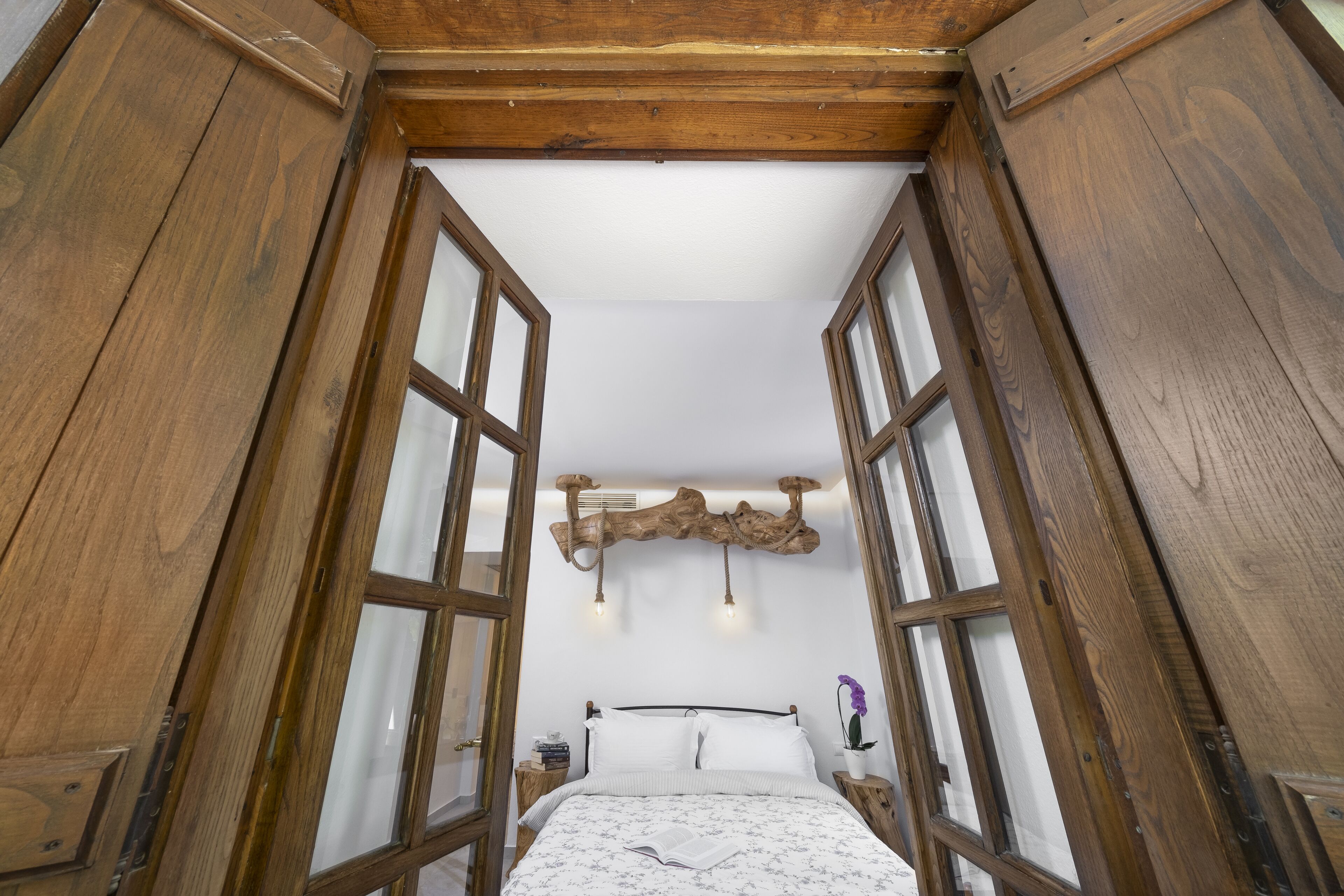 A bedroom with a bed, wooden headboard, and a window with a view.