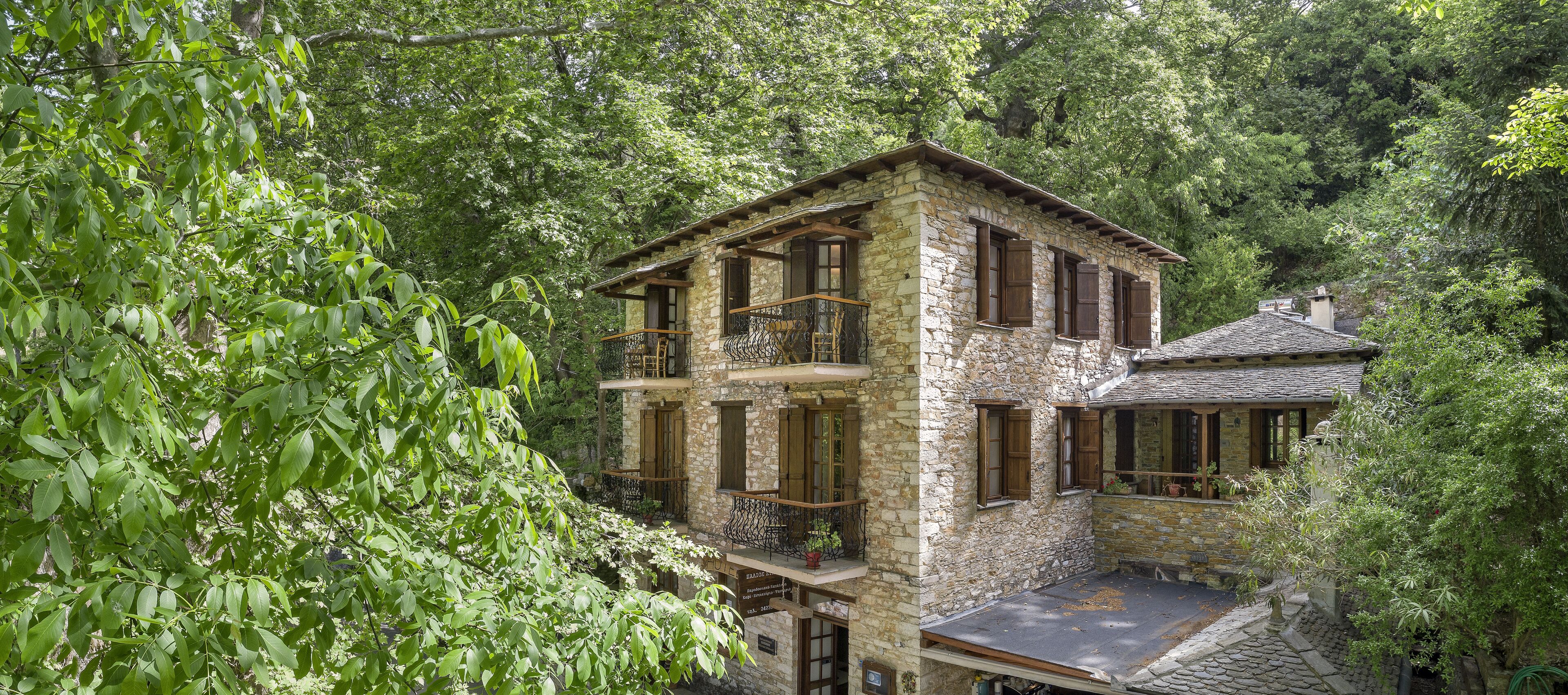 A stone building with multiple balconies, surrounded by lush greenery.
