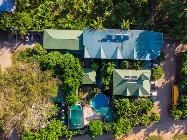 Vista aérea de una propiedad con varias edificaciones, piscina y una amplia zona verde con árboles.