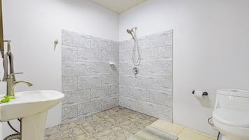Een badkamer met een douche, wastafel, toilet en betegelde vloer.