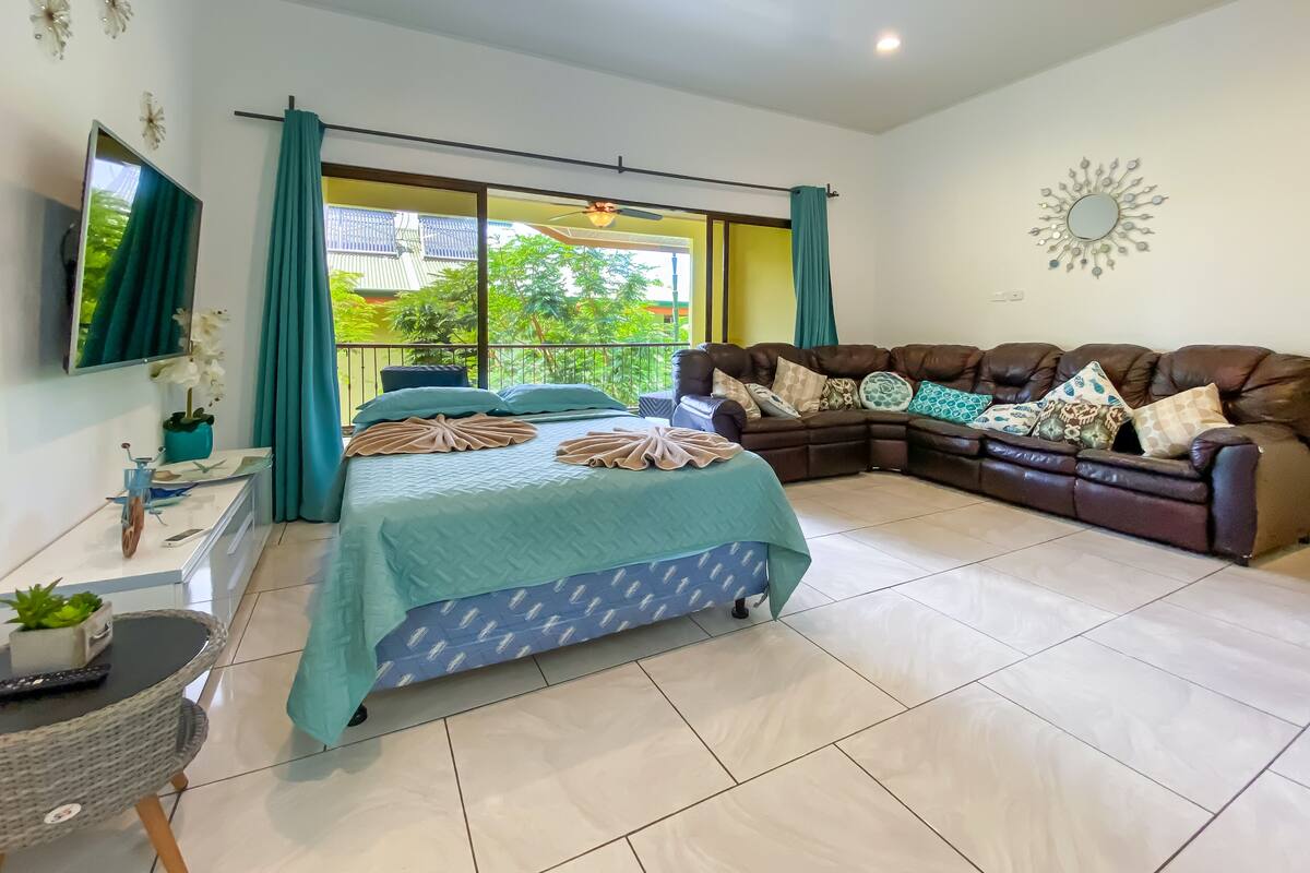 A modern living room with a sofa, a bed, and a TV.