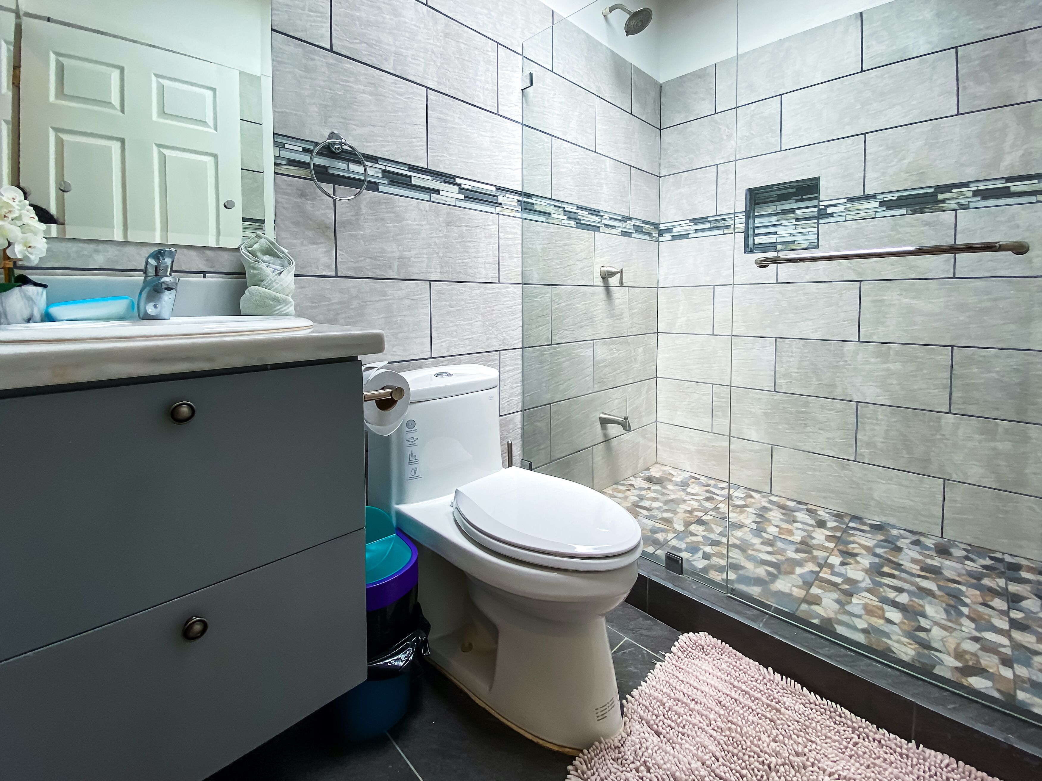 Un baño moderno con inodoro, lavamanos y cabina de ducha.